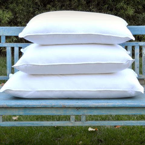 3 white, 180 thread count poly/cotton blend plush pillows stacked onto each other on a blue park bench