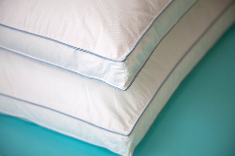 Two Climarest Cooling Gusset Pillows stacked atop one another. Zoomed into the corner. All white except there are two stripes parallels to one another and it kind of gives the allusion of creating a rectangle across the sides of the pillow without actually having connecting lines.