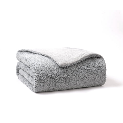 The Reversible Cooling Sherpa Blanket folded up in a square  Sherpa side out, cooling side of the blanket in. With one corner peaking out the cooling side.