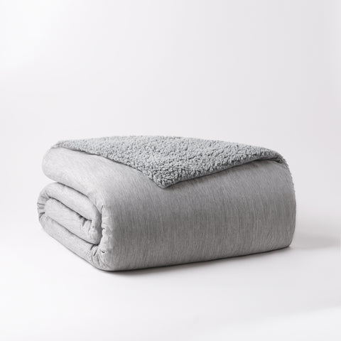 Reversible Cooling Sherpa Blanket with the Sherpa side folded inward and the cooling side outward. Except for the little corner of the blanket that is folded outward so you can see the Sherpa that's on the inside.