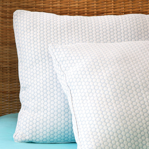 Two CoolMax pillows leaning on a wicker head board. The photo focusing on the left sides of the pillow but still getting a front angle. The pillow features a distinctive white and blue dotted pattern on the pillows.