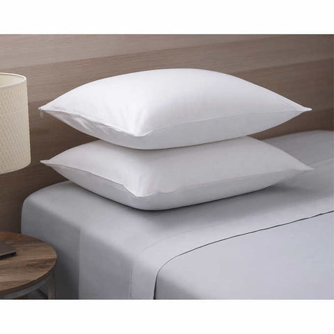 Two RDS White Duck Down Pillow stacked on top of each other on a bed. You can see on the top pillow on the top left corner a zipper dangling. The pillows are white.