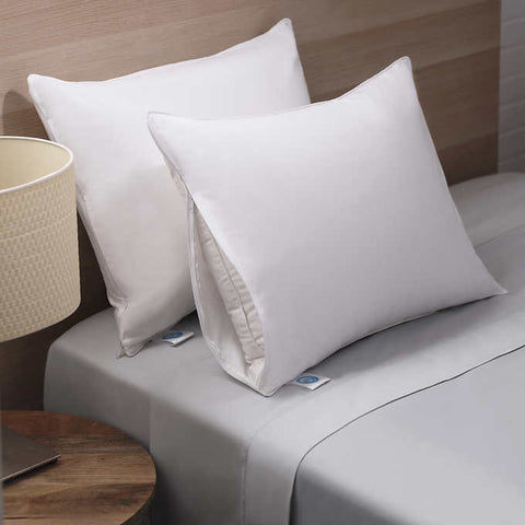  Two RDS White Duck Down Pillows are being showcased here. One leaning on a headboard, while the other leans on the first onw. The pillow that's on top is opened a bit on the side, to display the insert. On the left bottom corner of the both pillows is a white tag sticking out with the blue RDS certified logo.