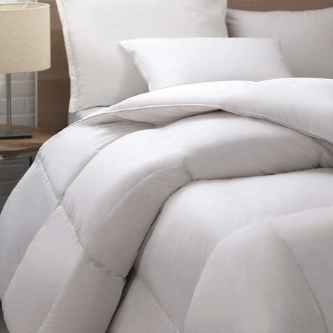Close up image of the head of a bed. You can clearly see the square stitching in the comforter. This exquisite comforter features a 400 thread count sateen cotton fabric that is intricately woven to create a down-proof barrier. This ensures that the premium high loft 700 fill power white down is securely contained within.
Designed to offer optimum loft and even distribution, this comforter boasts a baffle box construction with a 1" gusset.