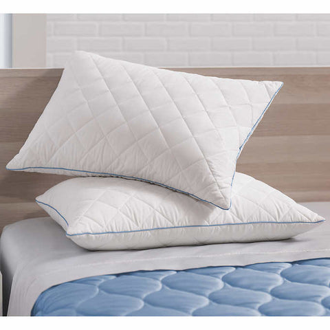 Two pillows with diamond shapes on them and blue stitching along the sides, lay on top of one another. The bottom pillow is straight while the top pillow is skewed and leaning on the head board. Crafted with a 300 thread count cotton cover infused with temperature-regulating ClimaRest®, these pillows are also quilted with Suprelle® Cool Night gel fiber for effective heat dissipation. Brown head board faded in the background.