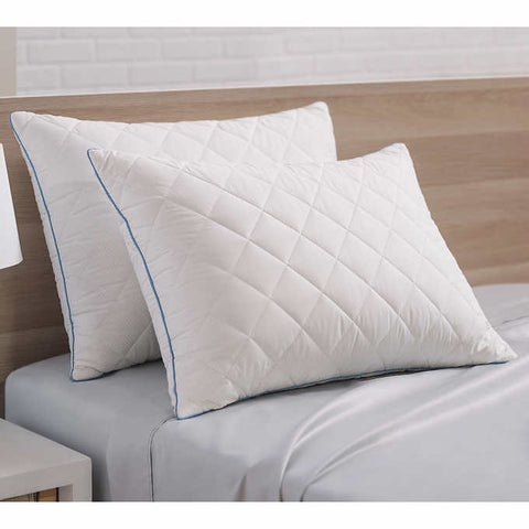 Two pillows with diamond shapes on them and blue stitching along the sides, leaning on a head board. Crafted with a 300 thread count cotton cover infused with temperature-regulating ClimaRest®, these pillows are also quilted with Suprelle® Cool Night gel fiber for effective heat dissipation. Brown head board faded in the background. 