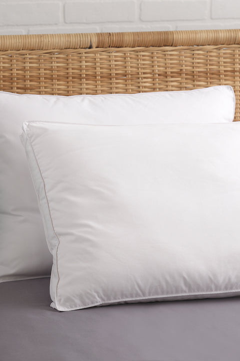 Two PureShield Gusset Pillows leaning on eachother and on a whickered brow headboard.