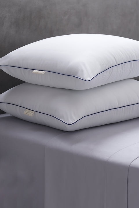Two Cozy Clouds Microfiber Pillows laying perfectly on top of each other. Both with a dark line going along the side of the pillows and a white tag sticking out.