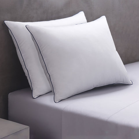 Two Cozy Clouds Microfiber Pillows leaning perfectly on top of each other and on a headboard. Both with a dark line going along the side of the pillows.