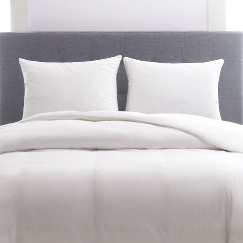 Herringbone Quilted Pillow 2-Pack side by side leaning on a dark grey headboard. The pillows have several horizontal lines running across it, with V shapes alternating facing up and down.