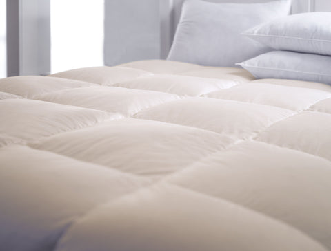 The Organic Cotton Down-Free Comforter laying flat with some pillows up top. Easily able to see the square design across the whole comforter.