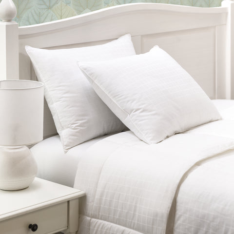 Two ComfortPlush Down Alternative Pillows leaning against each other against a headboard.