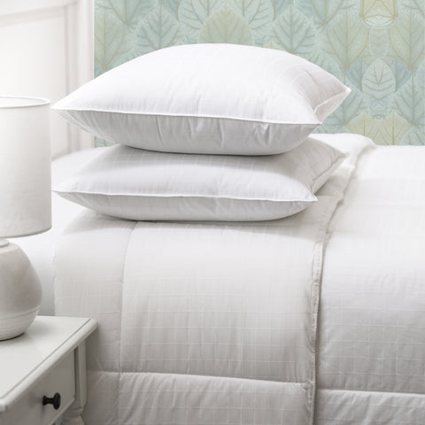 Two ComfortPlush Down Alternative Pillows stacked atop one another on top of a fully made bed.