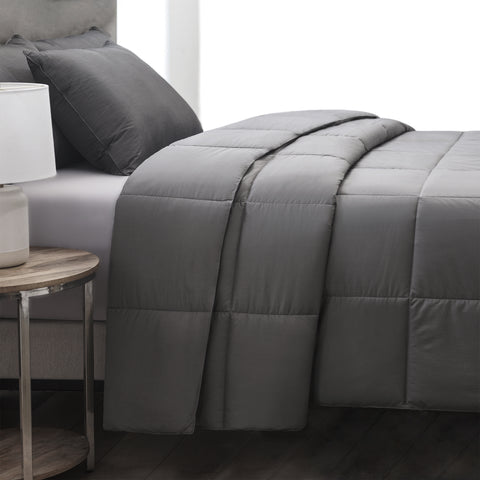 The Graphene Comforter aka the CharcoBlanket, is shown laying on a bed generously folded over itself at the top. With 420 thread count cover fabric. Large squares stitching running across the whole surface.