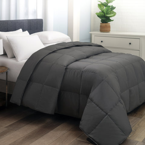 The Graphene Duvet aka the CharcoComforter, is shown laying on a bed generously folded over itself at the top. With 420 thread count cover fabric. Large squares stitching running across the whole surface.