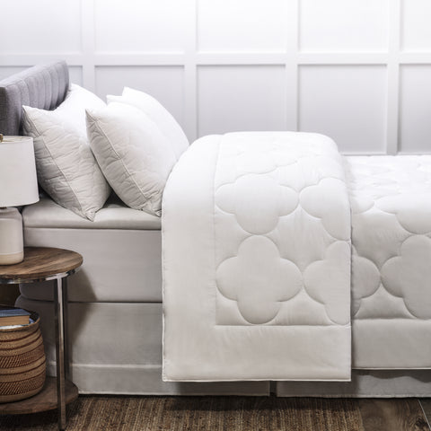 Side profile of a bed emphasizing a comforter with 8 inch frame with a 10 to 13 inch quilted cloud pattern in the center and is filled with high-quality, gel-fiber polyester filling with a 300 thread count cotton
