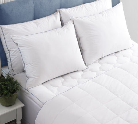 Four Climarest Cooling Gusset Pillows leaning on a blue head board of a bed. All white except there are two stripes parallels to one another and it kind of gives the allusion of creating a rectangle across the sides of the pillow without actually having connecting lines.
