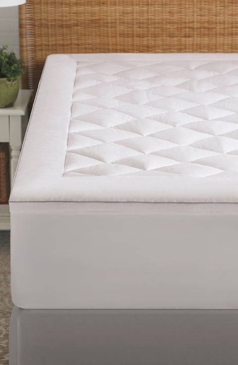 An image of the left half of the PureAssure Allergen Barrier Diamond Quilted Mattress Pad. As in the title, there are diamond shapes along the top of the mattress pad. There is a blank border around all the diamonds. The edges of the mattress mad are also plain, no diamond shapes.