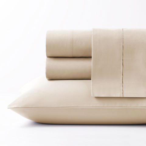 On a white background we have a full set of the Oat colored Microfiber Sheet Set. All perfectly folded up and layered on top of each other. Getting a side view of the pile this time and on the bottom of the pile is a pillow inside the oat colored pillow case.