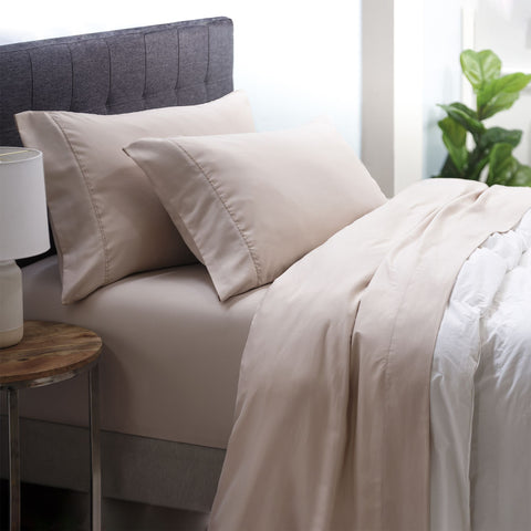 On a bed is the Oat colored Microfiber Sheet Set. the pillow cases are on two pillows the fitted sheet is on the bed and the top sheet is below the comforter. 