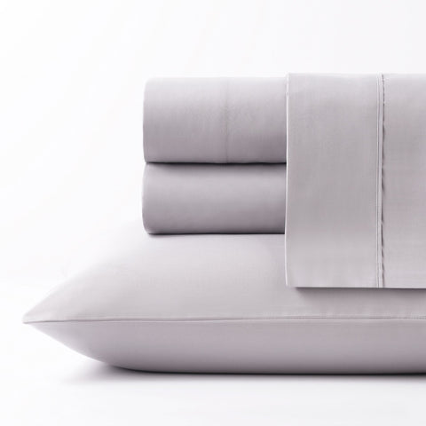 On a white background we have a full set of the Silver colored Microfiber Sheet Set. All perfectly folded up and layered on top of each other. Getting a side view of the pile this time and on the bottom of the pile is a pillow inside the silver colored pillow case.