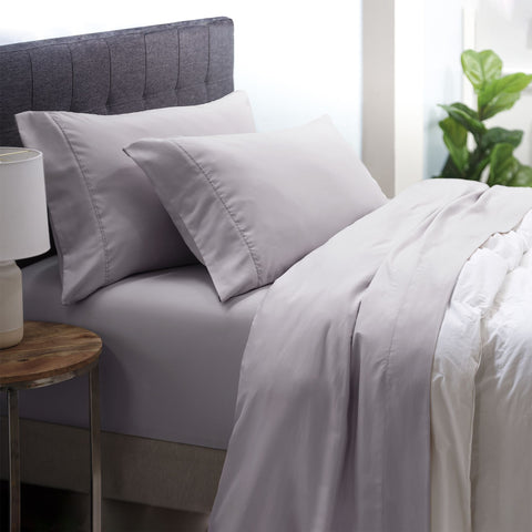 On a bed is the Silver colored Microfiber Sheet Set. the pillow cases are on two pillows the fitted sheet is on the bed and the top sheet is below the comforter. 