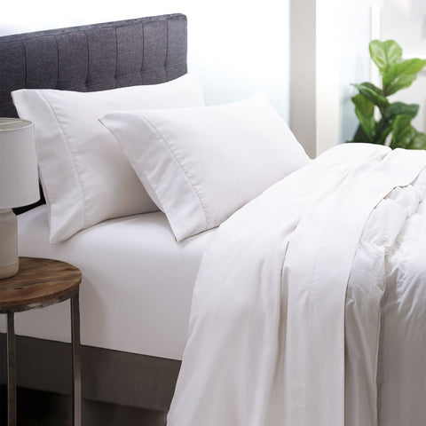 On a bed is the White colored Microfiber Sheet Set. the pillow cases are on two pillows the fitted sheet is on the bed and the top sheet is below the comforter. 