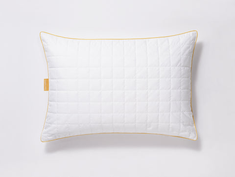 Pillow laying flat on a white surface. Squares stitching across the surface. Classic Simmon's Yellow line around the ends and a matching yellow Simmons tag on the left side. 230 thread count quilted cover.