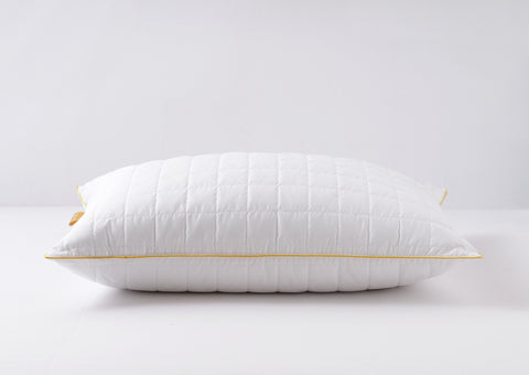 Pillow laying flat on a white surface. Getting a side look of the pillow. Squares stitching across the surface. Classic Simmon's Yellow line around the ends and a matching yellow Simmons tag on the left side. 230 thread count quilted cover.