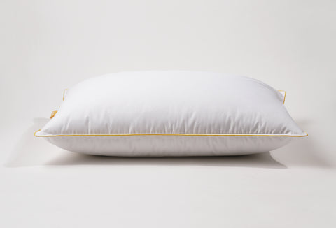 Side profile of the pillow. White pillow laying flat on a white surface. Classic Simmon's Yellow line around the ends and a matching yellow Simmons tag on the left side. 230 thread count quilted cover.