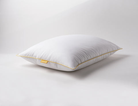 White pillow laying flat on a white surface. Classic Simmon's Yellow line around the ends and a matching yellow Simmons tag on the left side. 230 thread count quilted cover.