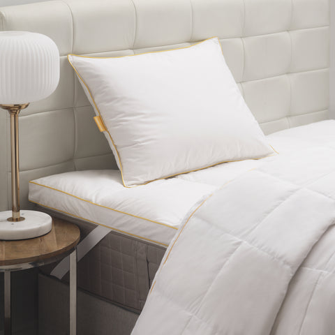 White pillow laying on a white headrest. Classic Simmon's Yellow line around the ends and a matching yellow Simmons tag on the left side. 230 thread count quilted cover.