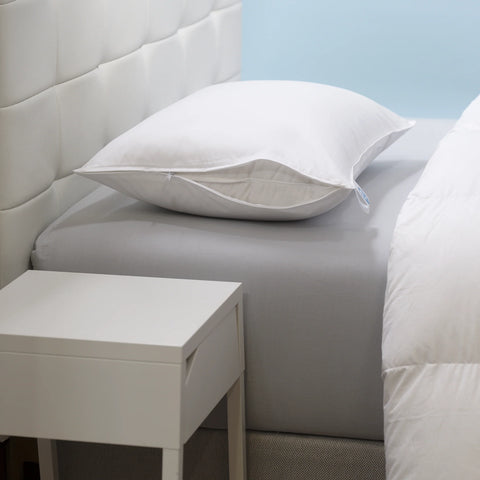 A side view of the head of a bed. With as singular pillow laying flat on the bed, with the pillow case 3/4 of the way open so you can see the pillow. 400 thread count sateen cotton zipper removable cover that allows for easy care.&nbsp;The inner cover is a 233 thread count cotton that is woven tightly to create a down-proof barrier that ensures the high loft 650 fill power white goose down stays inside. Beside the bed is a white night stand. The is white headboard with square design going up and down. 