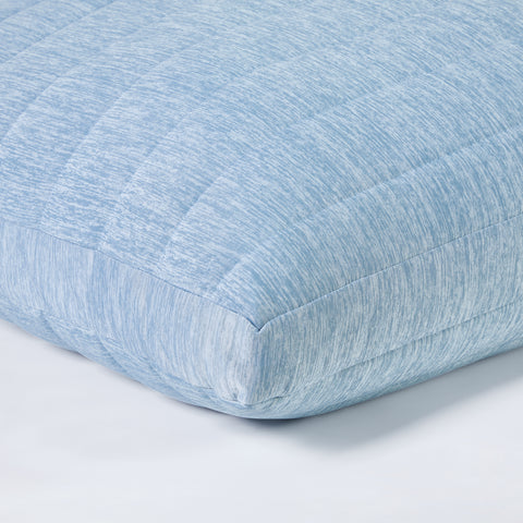 Super zoomed in picture of the corner of the light blue pillow, allowing you to see the detailed stitching of the pillow that makes square patterns.