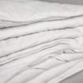 Zoomed in photo of a comforter folded up, the image emphasizes the many folds in the blanket.  The 100% cotton cover is made with a 233-thread count that makes for a soft and extremely durable comforter. 
