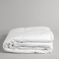 A white background. In the bottom have of the picture, is our basic down alternative comforter, folded in a perfect square. We are getting a side view of the item.  The 100% cotton cover is made with a 233-thread count that makes for a soft and extremely durable comforter. 