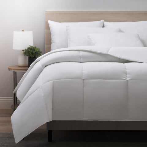 Classic Peachy Down Alternative Twin Comforter. Despite the name "peachy" the color of the blanket is in fact white. Large blanket laying atop a bed. With large square stitching across the whole thing. 