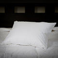 On a bed is the Perfect White Goose Down Pillow - 50/50 Fill - Medium Plush Support leaning back and to the side.