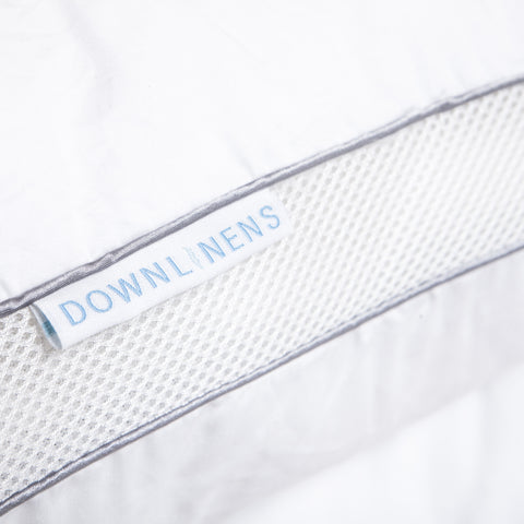 PowerNap Celliant Fiber Blend Pillow (Soft) (Set of 2). Zoomed in on one side of a pillow, where there are two blue parallels lines with little dots filling up the space between. Then a white tag with blue text that reads "DOWNLINENS."