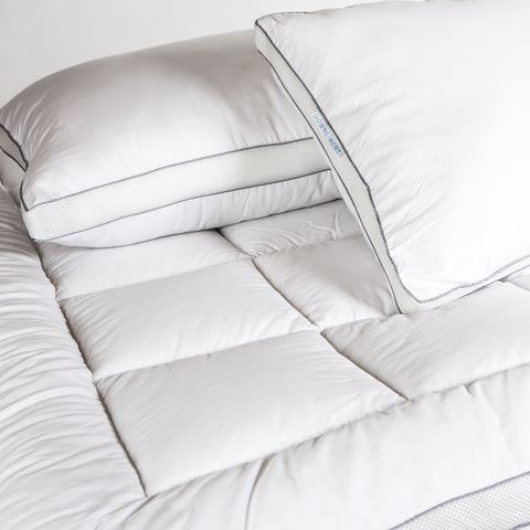 PowerNap Celliant Fiber Blend Mattress Pad can see the large squares on the surface. There are some pillows on top to create the scene.