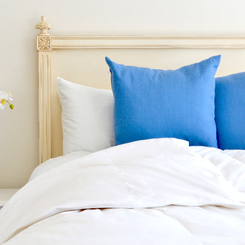 On a bed appears three pillows, one white and two bright blues. Laying in front of the pillows is  the comforter which is a 100% cotton cover and is made with a 233-thread count that makes for a soft and extremely durable comforter. 