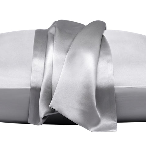 On a white background is a pillow laying flat. The pillow is in the gray silk pillow case, with another gray pillow case on the center of the pillow, overlapping on itself. This image is almost trying to emphasize the pillowcase that's resting on top, by zooming in.