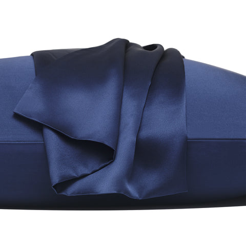 On a white background is a pillow laying flat. The pillow is in the navy silk pillow case, with another navy pillow case on the center of the pillow, overlapping on itself. This image is almost trying to emphasize the pillowcase that's resting on top, by zooming in.